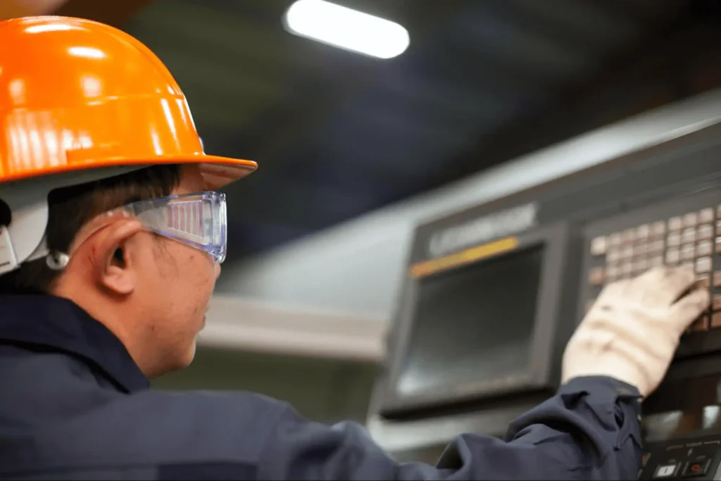 Trabalhador ajustando controles de guilhotina industrial moderna
