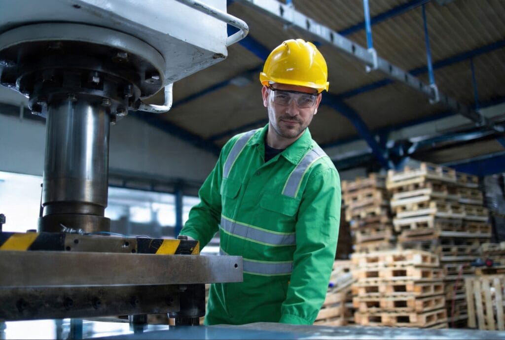 Operador industrial utilizando prensa de conforma&ccedil;&atilde;o de metais em ambiente fabril.